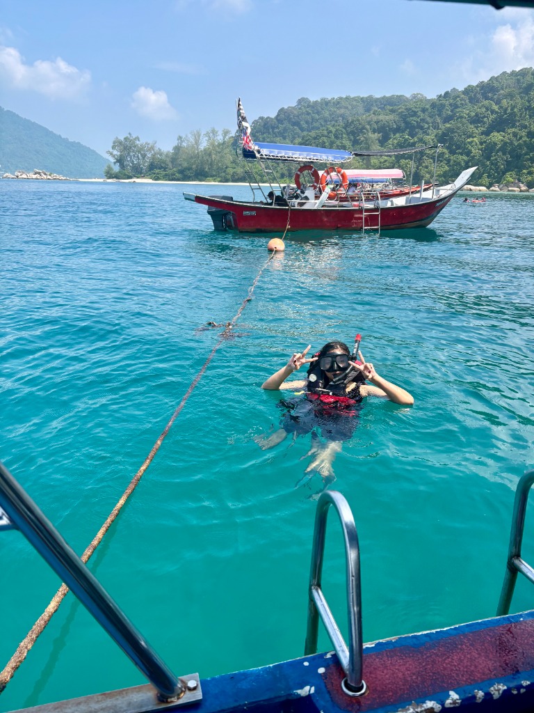 Snorkeling in clear turquoise water beside a boat.