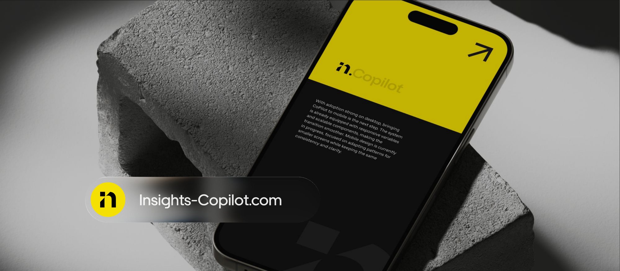 A phone resting on a concrete block showing the CoPilot mobile concept in yellow and black.